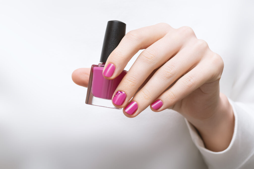 female hand with pink nail design holding nail polish bottle|Nailcarewithsam