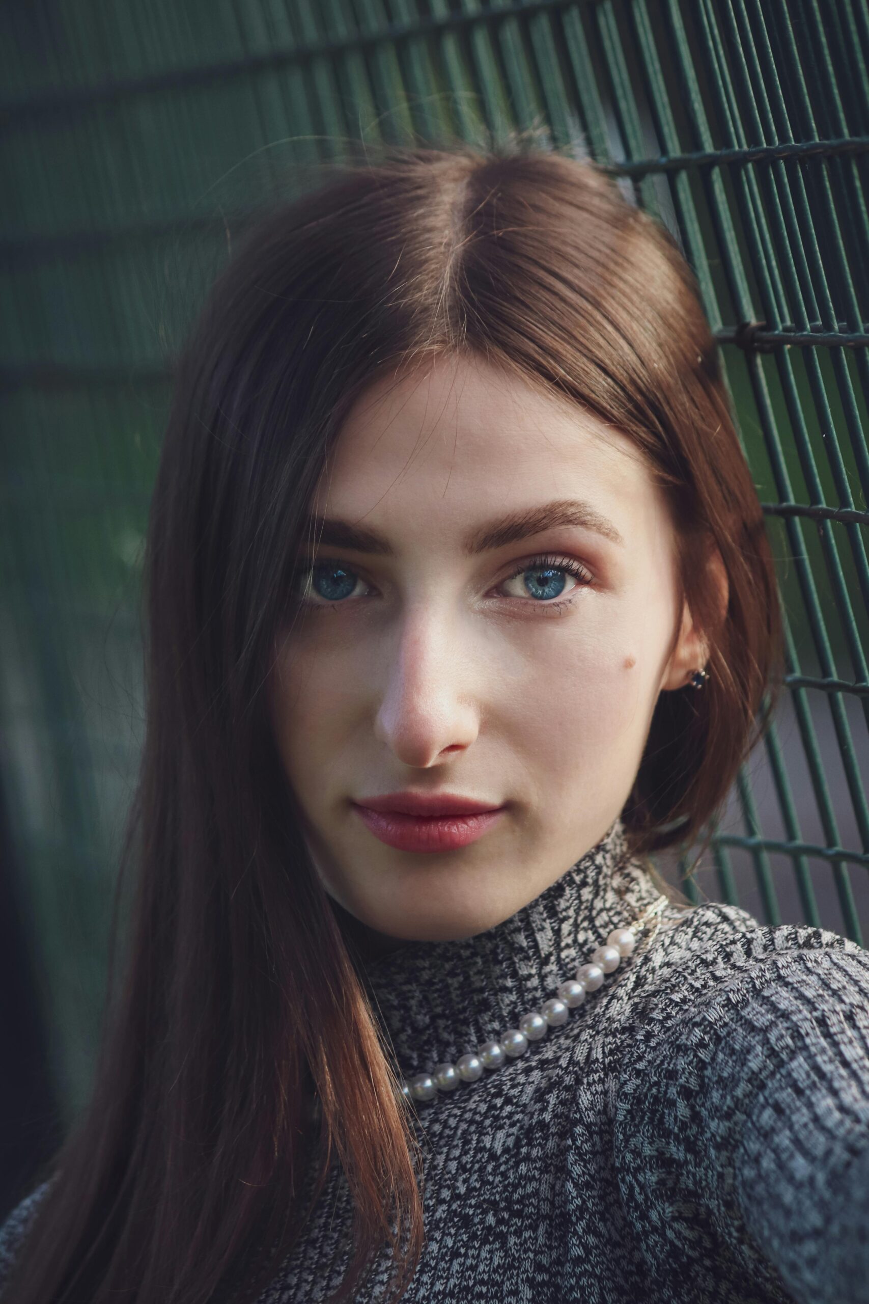 Close-up portrait of a young woman with blue eyes and pearls, showcasing elegant beauty.|Nailcarewithsam