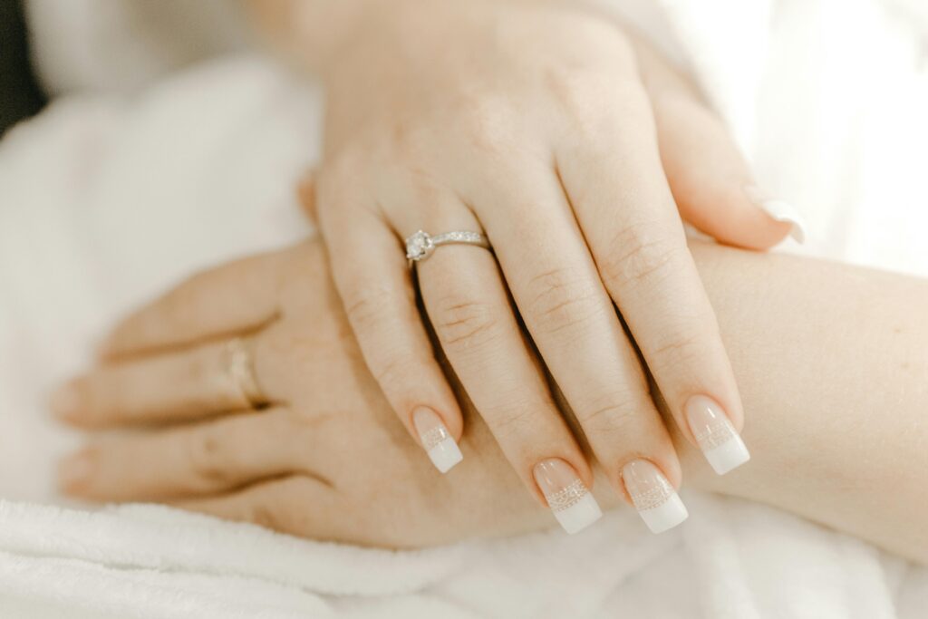 From above of hands of crop anonymous woman with classic manicure and ring with precious stone on wedding day|Nailcarewithsam